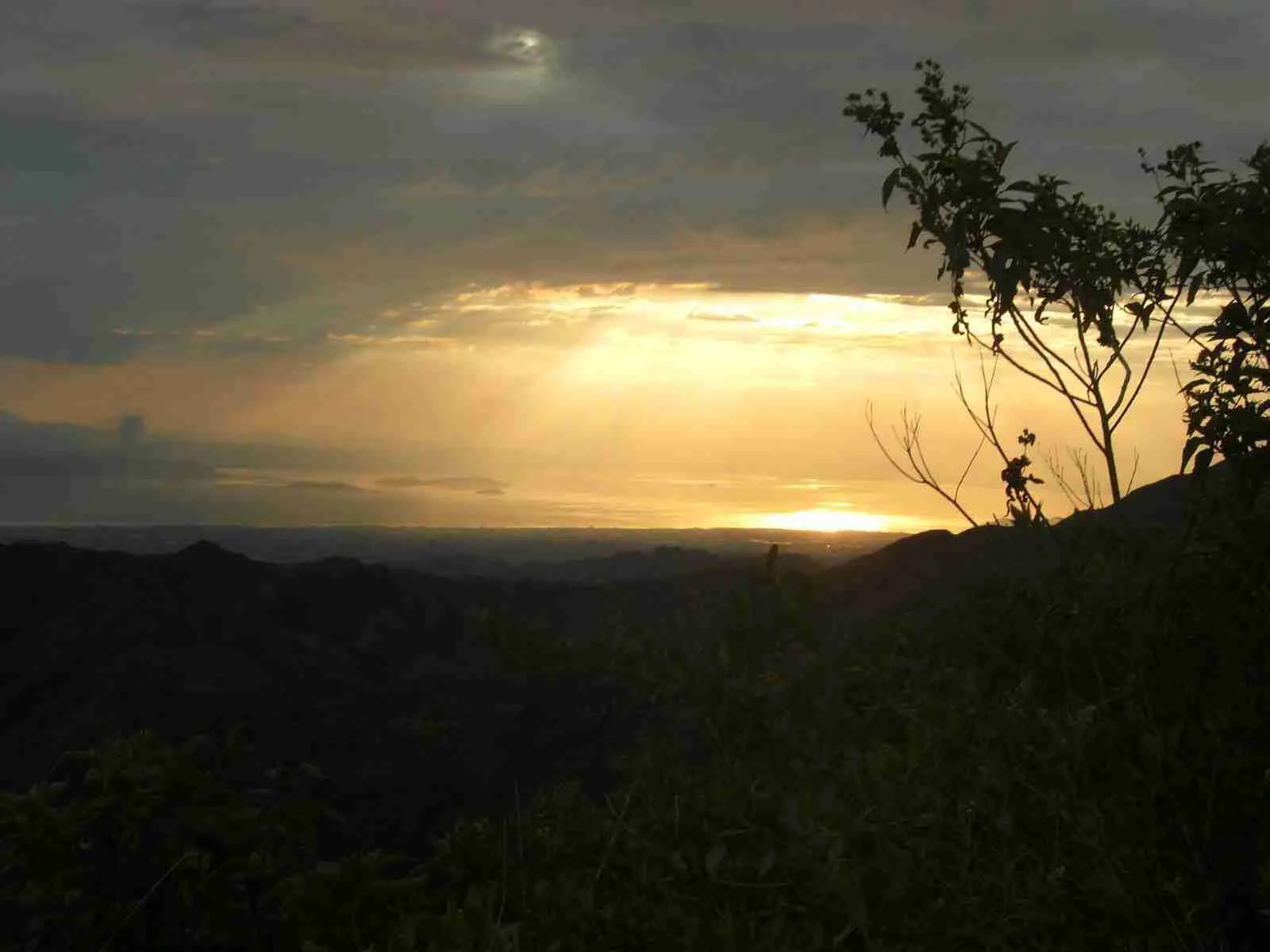 Rayos de sol entre las nubes sobre la silueta de un monte