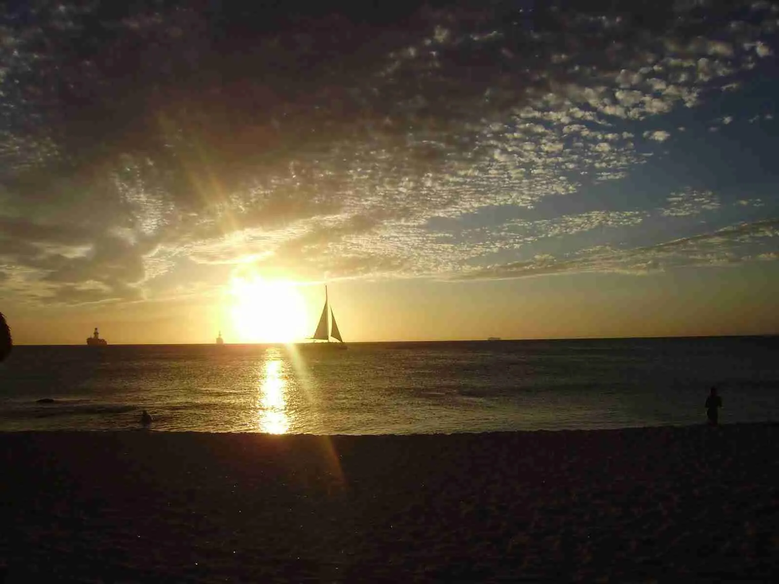 Puesta de sol en el mar con un velero a contraluz