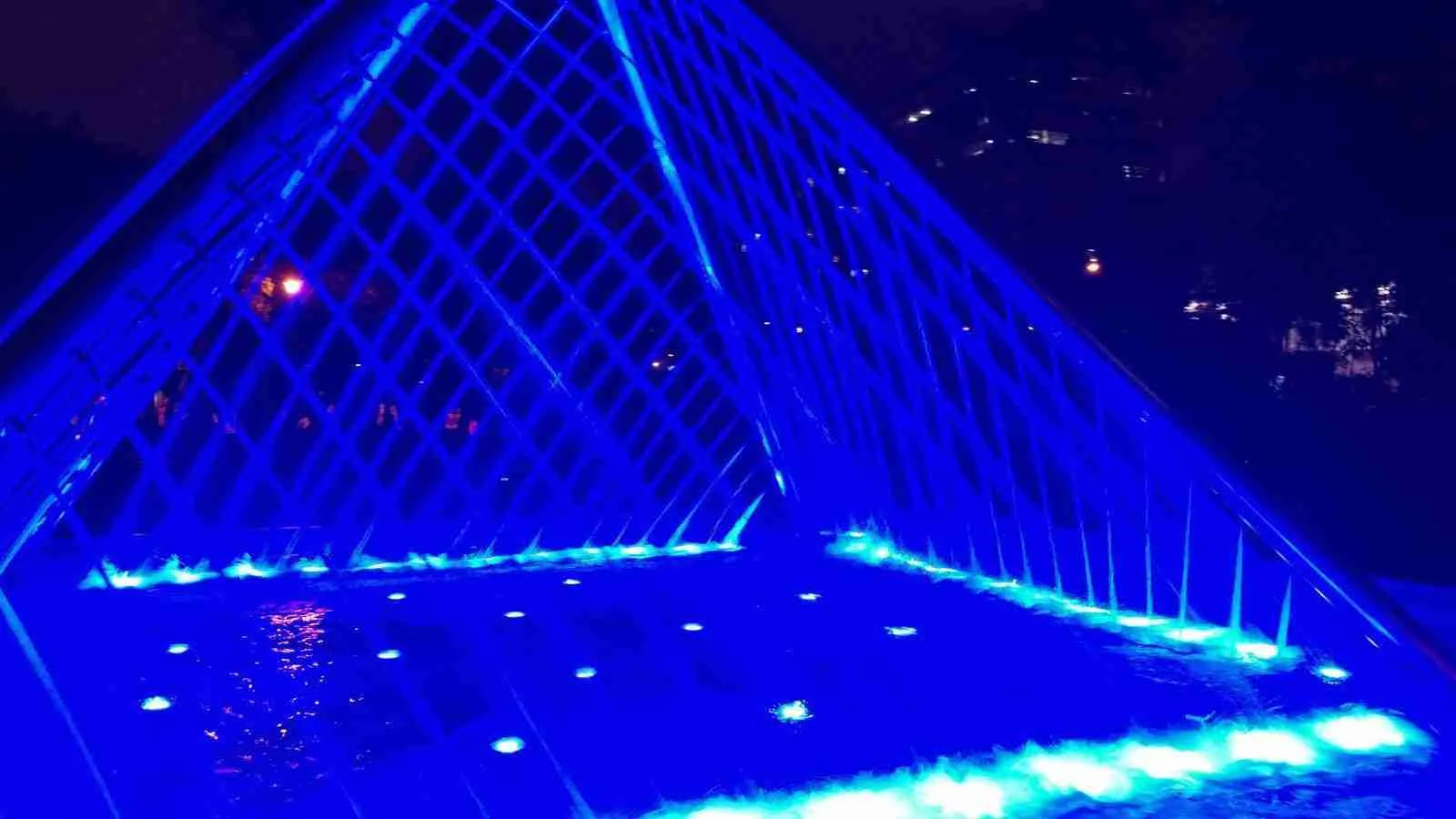 Estructura de cristal en forma de pirámide iluminada de azul por la noche