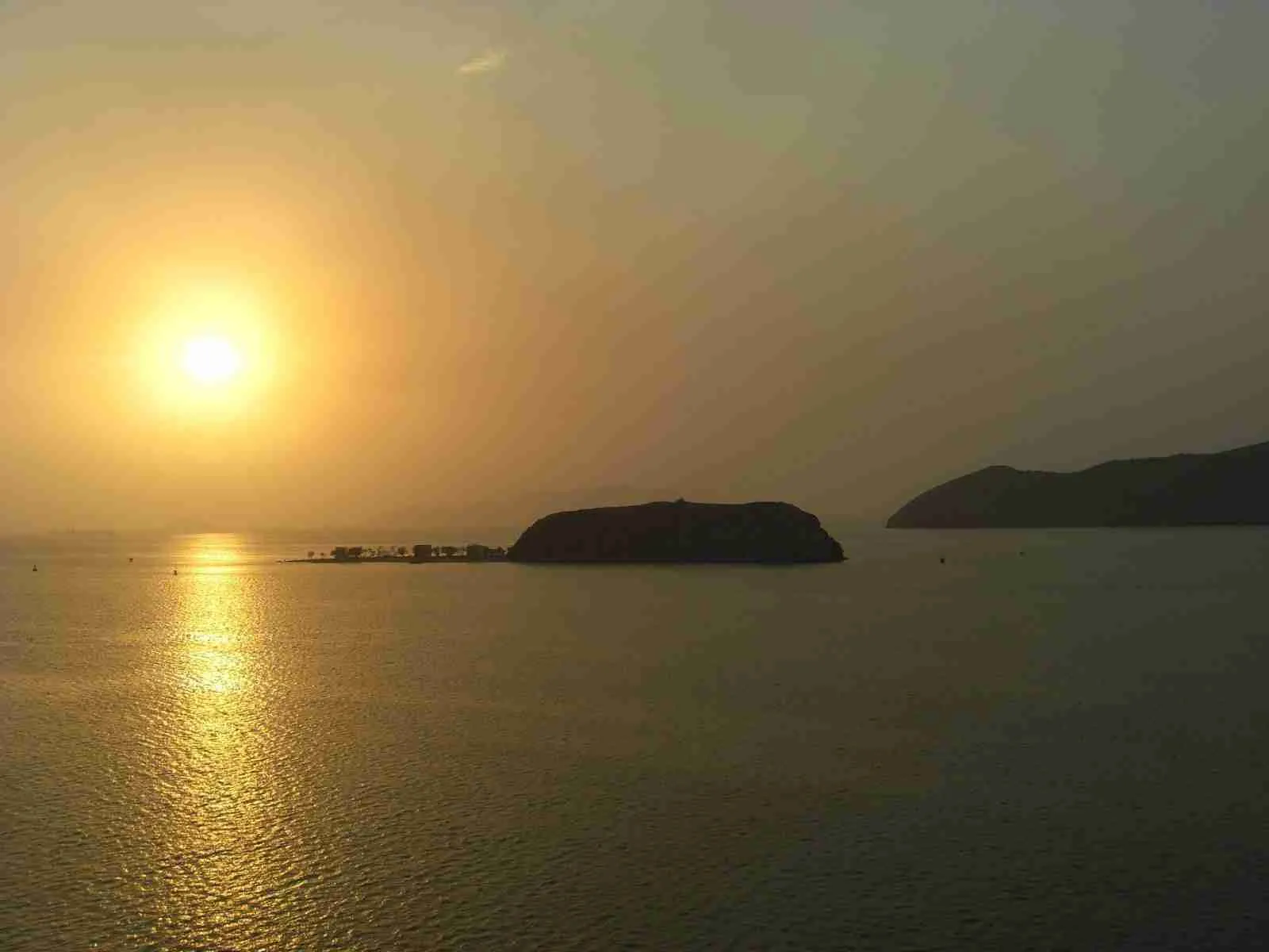 Sol del atardecer reflejado en el mar junto a una isla