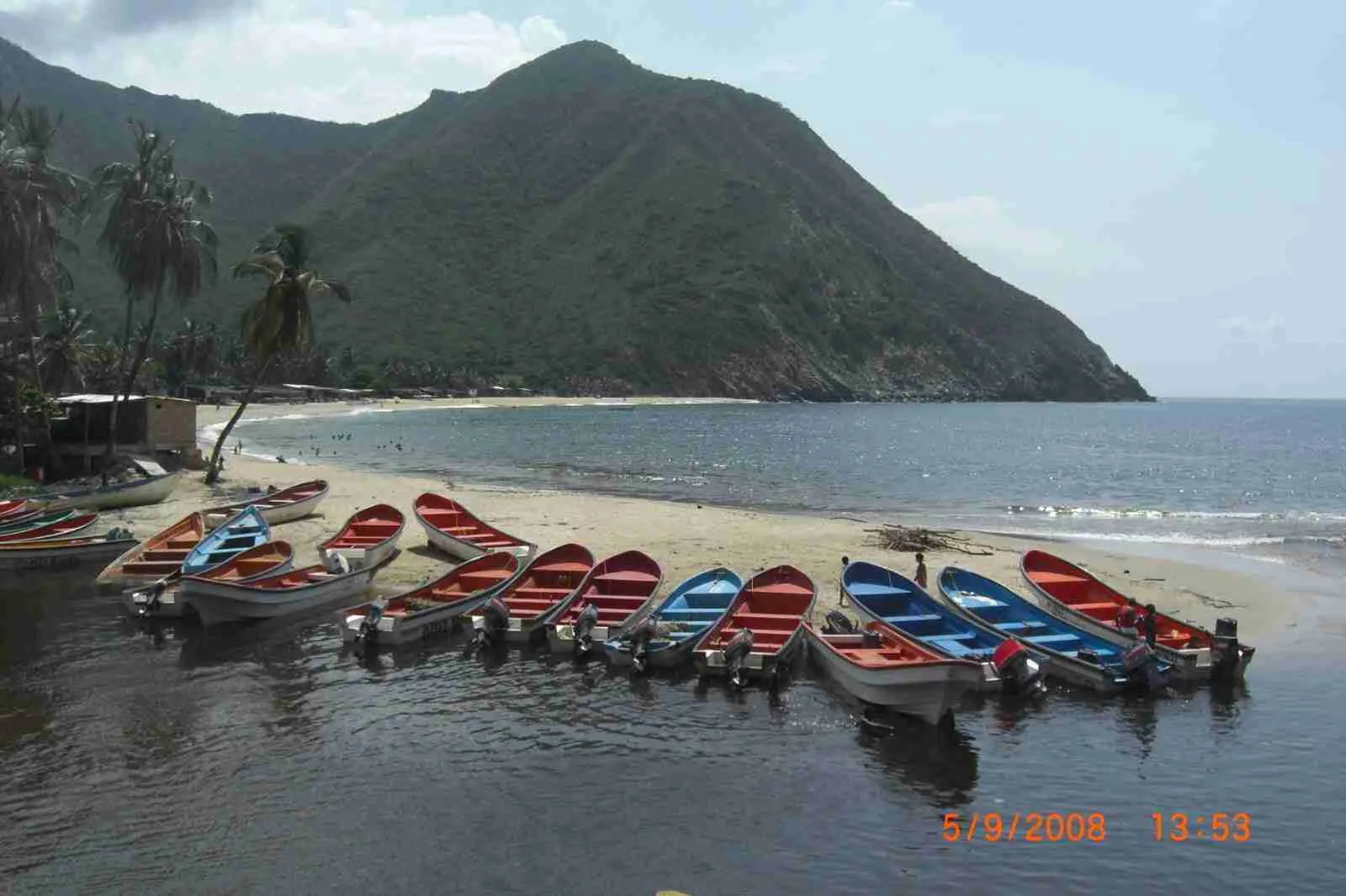 Lanchas de pescadores de colores en la orilla de una playa al pie de un cerro