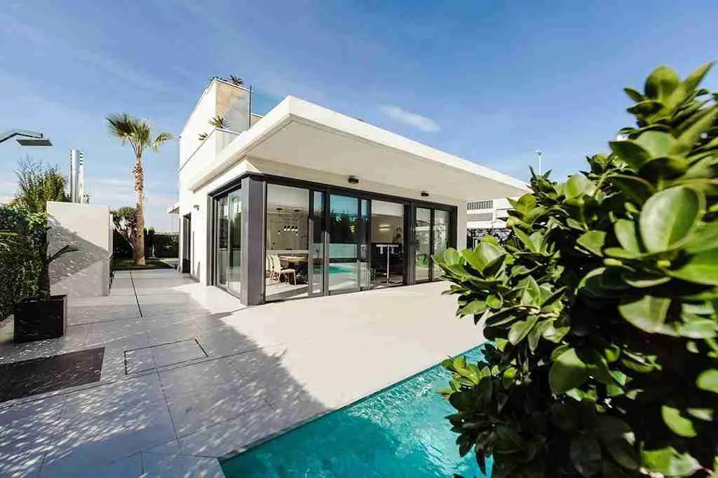 Casa moderna de color blanco con grandes ventanales, jardín y piscina