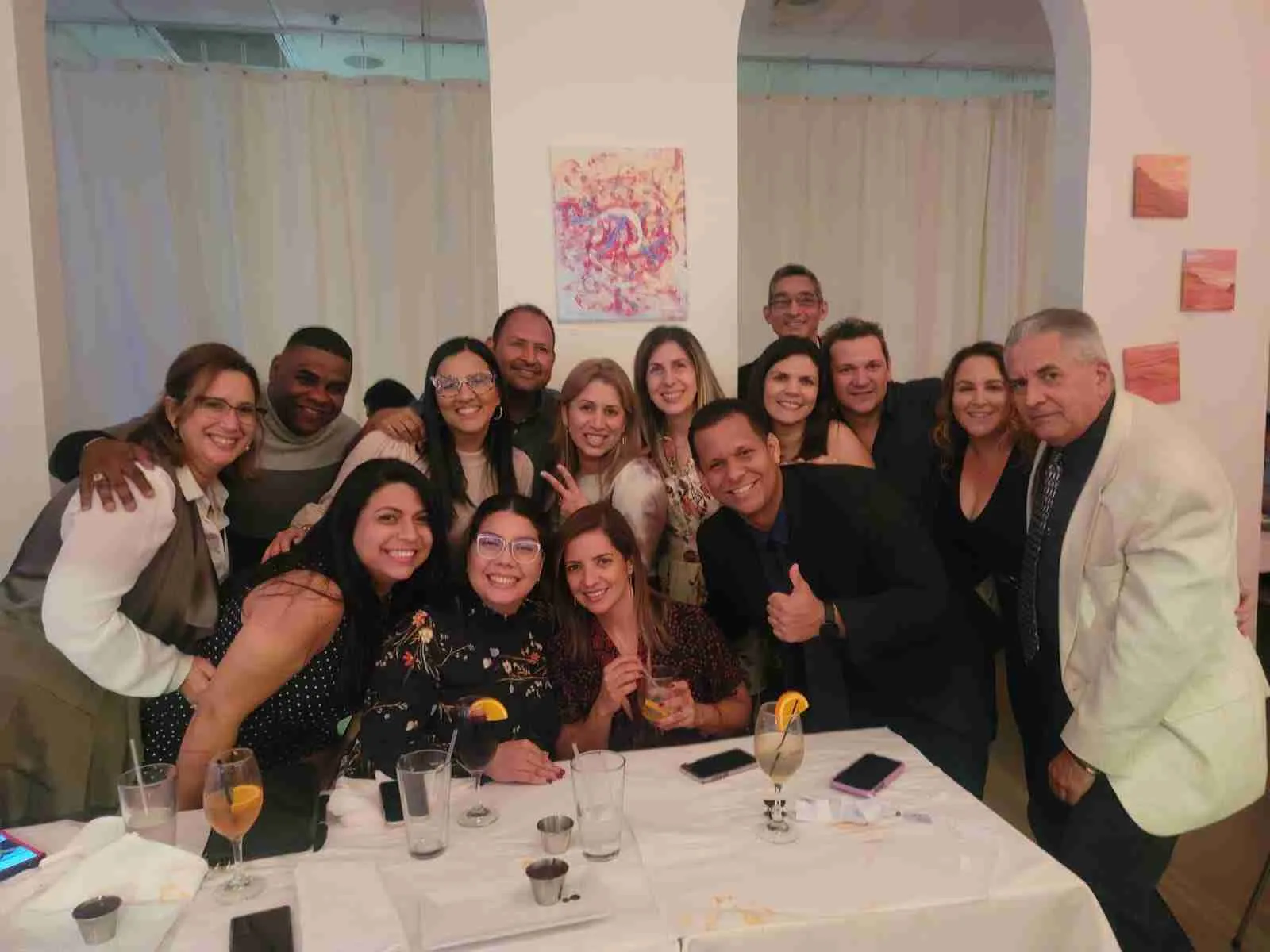 Grupo de compañeros posando alrededor de una mesa con copas en un restaurante