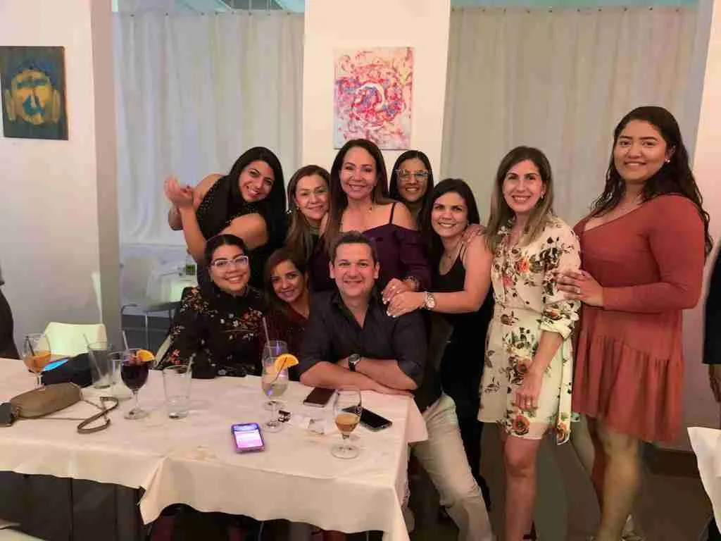 Grupo de mujeres y un hombre posando junto a una mesa con bebidas en un restaurante