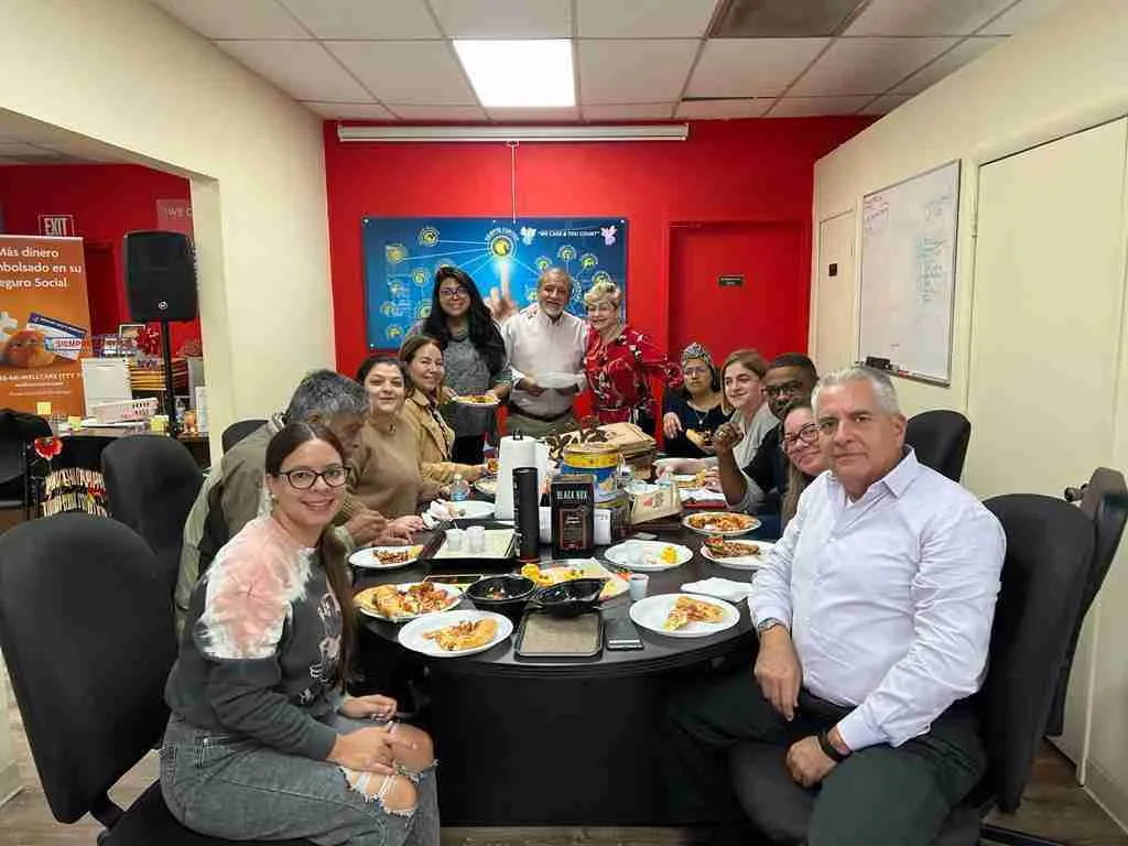 Comida de equipo alrededor de una mesa redonda en una oficina con paredes rojas