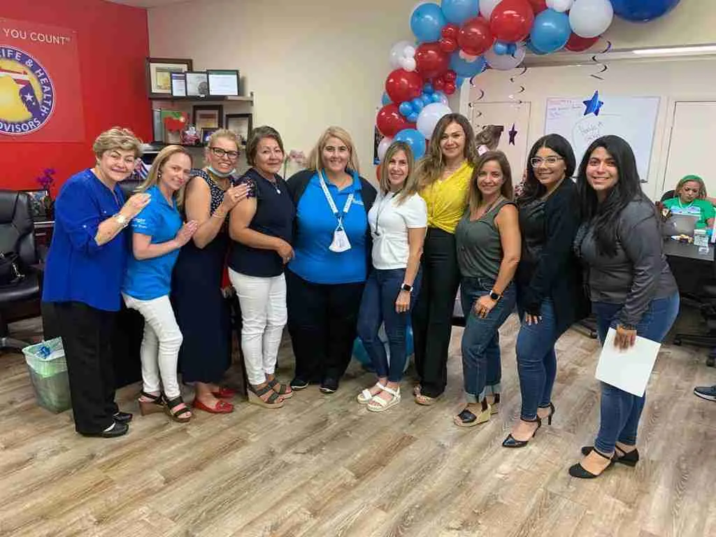 Grupo de mujeres posando en fila en una oficina decorada con globos rojos, blancos y azules