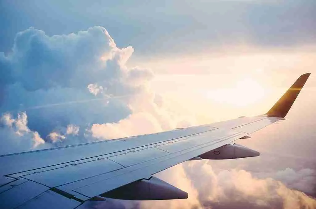 Ala de un avión en vuelo sobre las nubes al atardecer